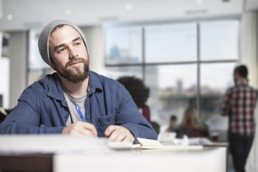 Mann mit Notizbuch am Schreibtisch im Büro denkt nach - ZEF12560