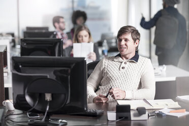 Smiling man at desk in office - ZEF12567
