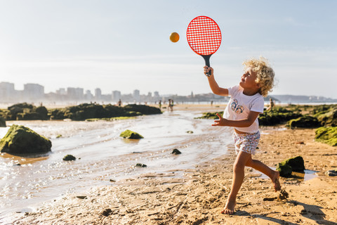 Kleiner Junge spielt am Strand mit Paddeln, lizenzfreies Stockfoto