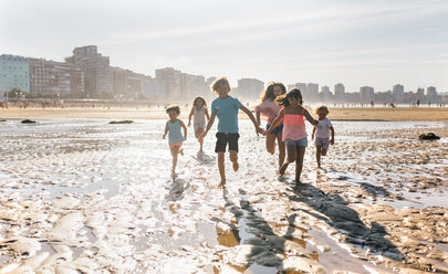 Gruppe von sechs Kindern, die gemeinsam am Strand laufen - MGOF02847