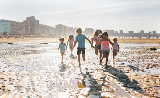 Gruppe von sechs Kindern, die gemeinsam am Strand laufen - MGOF02847