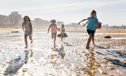 Group of five children running together on the beach - MGOF02848