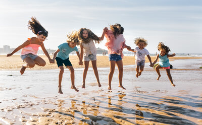 Gruppe von sechs Kindern, die am Strand in die Luft springen - MGOF02850