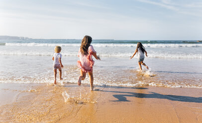 Back view of three children running into the sea - MGOF02852