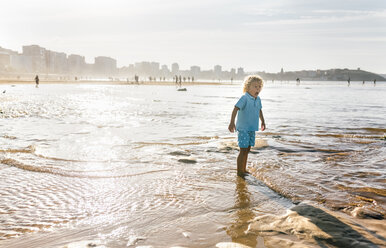 Little boy standing in cold water on the beach - MGOF02859