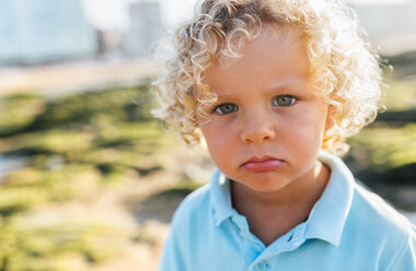 Portrait of little boy pouting mouth on the beach - MGOF02860