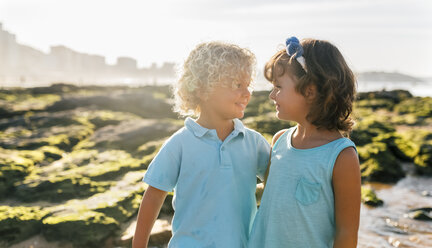 Happy little boy and girl face to face on the beach - MGOF02861