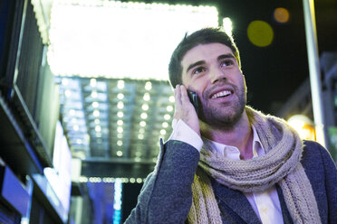 Smiling man on cell phone in the city at night - ABZF01808