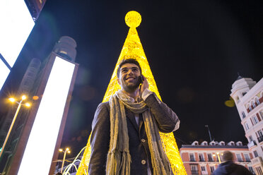 Smiling man on cell phone in the city at night - ABZF01817