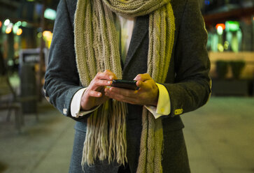 Nahaufnahme eines Mannes, der nachts in der Stadt sein Mobiltelefon benutzt - ABZF01818