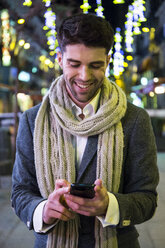 Mann benutzt sein Handy in der Stadt bei Nacht - ABZF01820