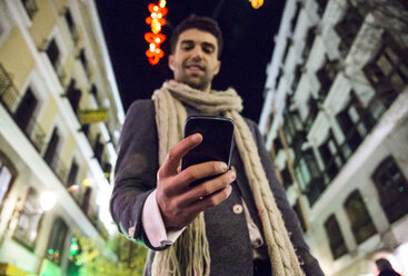 Mann benutzt sein Handy in der Stadt bei Nacht - ABZF01823