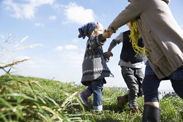 Three children playing ring-a-ring-a-roses in meadow - FSF00669