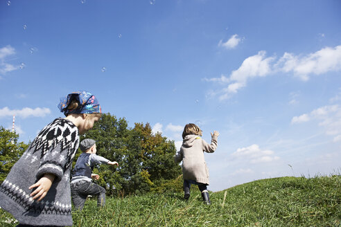 Drei Kinder spielen auf einer Wiese - FSF00671