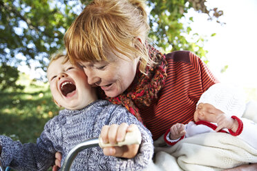 Glückliche Mutter mit Sohn und Baby in der Natur - FSF00674