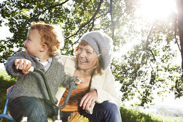 Happy mother with son on tricycle in the nature - FSF00679