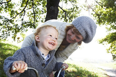 Glückliche Mutter mit Sohn auf Dreirad in der Natur - FSF00680