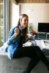 Happy young woman eating a healthy dessert at home - VABF01064