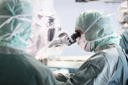 Neurochirurg schaut während einer Operation durch das Mikroskop - MWEF00116