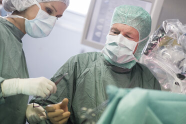 Krankenschwester im Operationssaal bei der Übergabe eines Instruments während einer Operation - MWEF00128