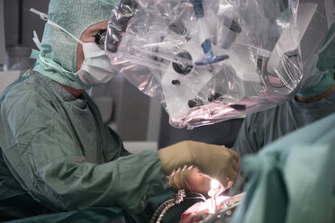 Neurochirurg schaut während einer Operation durch das Mikroskop - MWEF00129