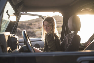 Woman sitting in car at sunset - SIPF01387