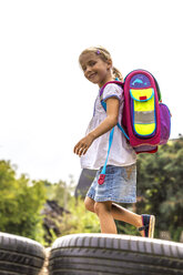 Lächelndes kleines Mädchen mit Schultasche auf dem Spielplatz - JFEF00832