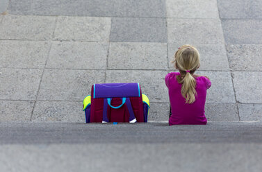 Back view of little girl with school bag sitting on stairs - JFEF00841