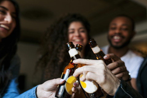 Vier Freunde stoßen mit Bierflaschen an, Nahaufnahme, lizenzfreies Stockfoto