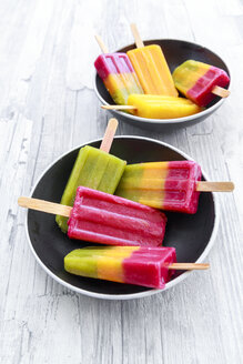 Two bowls of various homemade fruit smoothie ice lollies - SARF03144