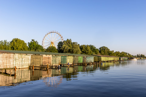 Deutschland, Rechlin, Blick auf Bootshäuser mit Riesenrad im Hintergrund, lizenzfreies Stockfoto