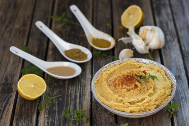 Schale mit Hummus und Zutaten auf Holz - YFF00627