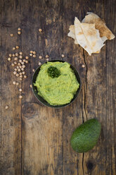 Bowl of avocado hummus, avocado, chick-peas and flat bread on dark wood - LVF05821