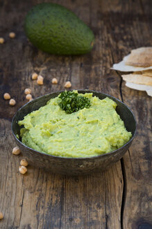 Schale mit Avocado-Hummus, Avocado, Kichererbsen und Fladenbrot auf dunklem Holz - LVF05822