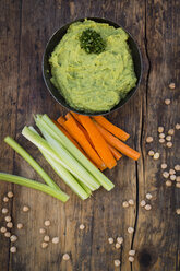 Schale mit Avocado-Hummus, Kichererbsen und Crudites auf dunklem Holz - LVF05824