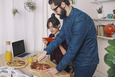 Junges Paar isst Pizza und trinkt Saft zum Mittagessen, Frau macht Fotos mit Smartphone - RTBF00623