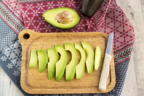 Sliced avocado and knife on chopping board stock photo