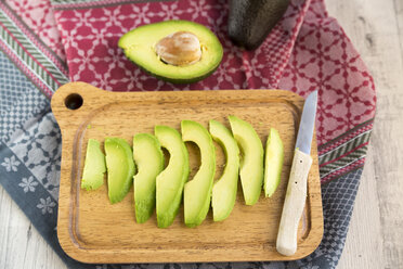Sliced avocado and knife on chopping board - SARF03157