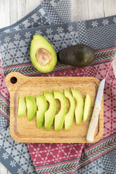 Sliced avocado and knife on chopping board - SARF03158