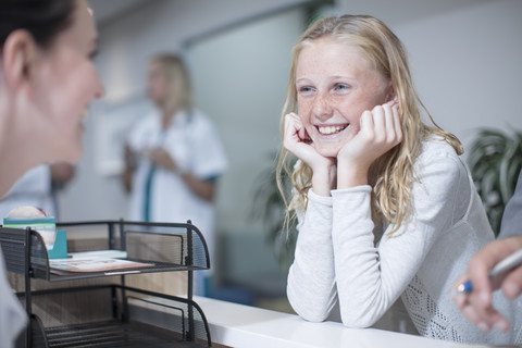 Glückliches Mädchen an der Rezeption eines Krankenhauses, lizenzfreies Stockfoto