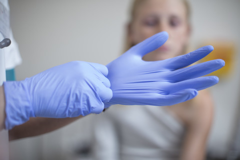 Arzt zieht blaue Latexhandschuhe an, lizenzfreies Stockfoto