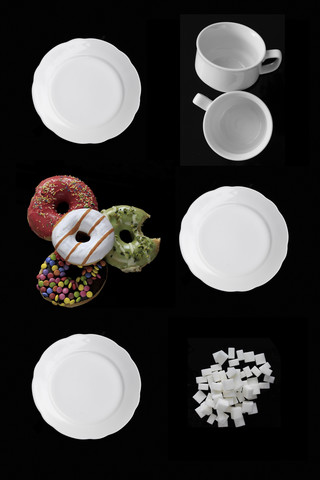 Weißes Geschirr, Krapfen und Zuckerwürfel auf schwarzem Grund, lizenzfreies Stockfoto