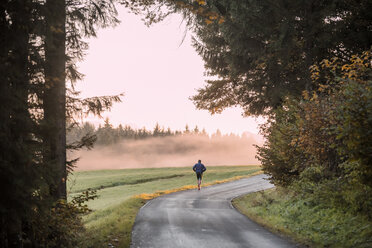 Back view of man jogging on country road in the evening - WVF00829