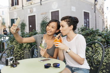 Italy, Padua, two young women taking selfie at sidewalk cafe - ALBF00073