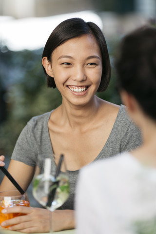 Porträt einer glücklichen jungen Frau in einem Straßencafé mit ihrer Freundin, lizenzfreies Stockfoto