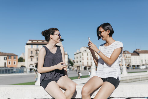 Italy, Padua, young woman taking picture of her friend with smartphone - ALBF00094