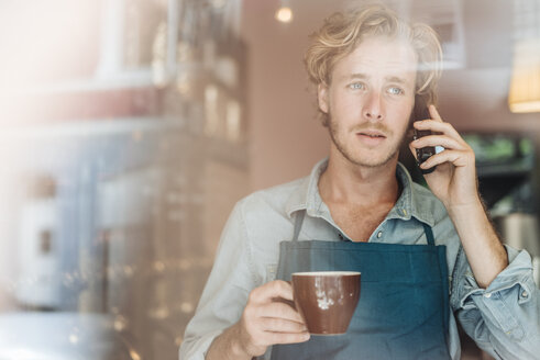 Kaffeeröster in seinem Geschäft beim Telefonieren - KNSF00903