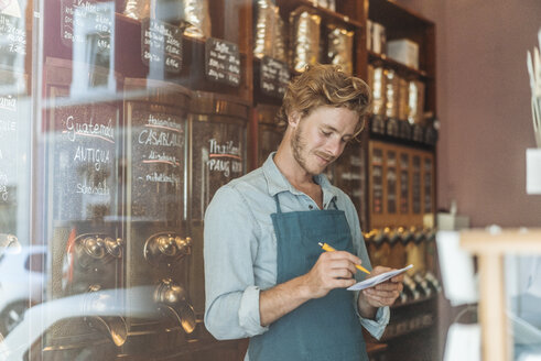 Kaffeeröster macht sich Notizen in seinem Geschäft - KNSF00912