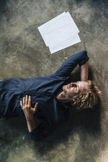 Man lying on floor next to papers - KNSF00918