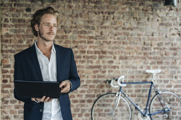 Businessman with laptop looking away - KNSF00937